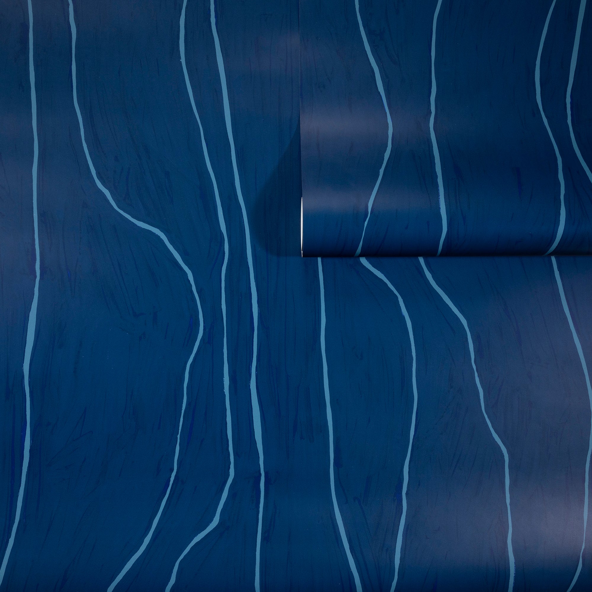 Deep navy blue wallpaper with abstract light blue wavy vertical lines, partially unrolled to showcase the pattern.