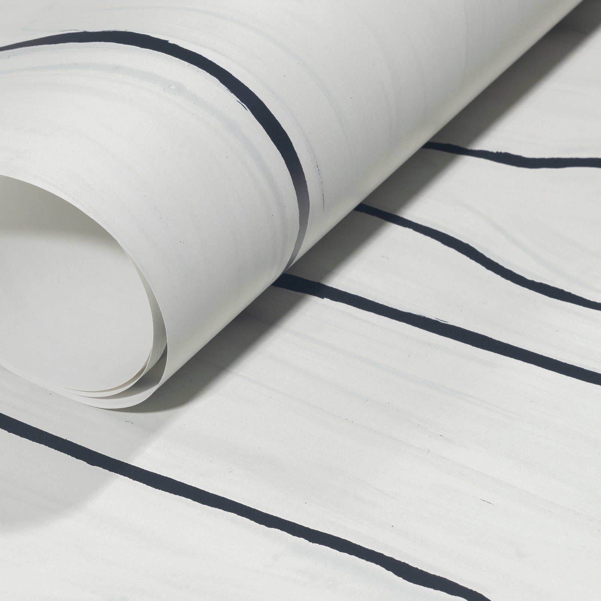 Rolled-up white wallpaper with striking black wavy stripes, showcasing its contemporary and minimalist design