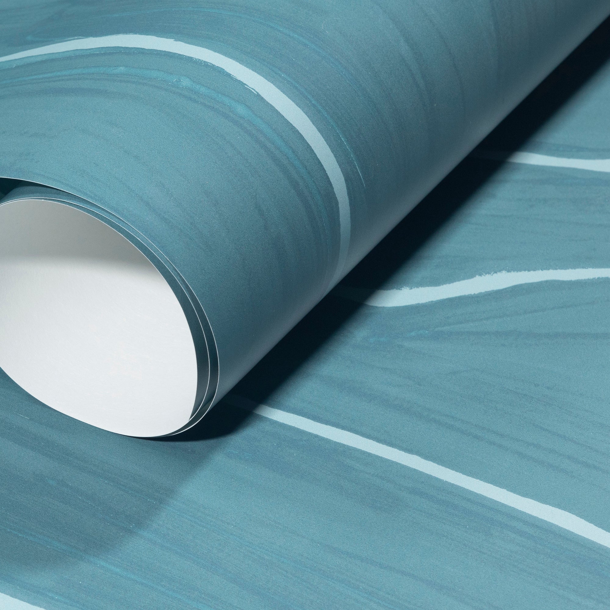Rolled-up teal wallpaper with elegant white wavy stripes, showcasing its subtle texture and sophisticated style.