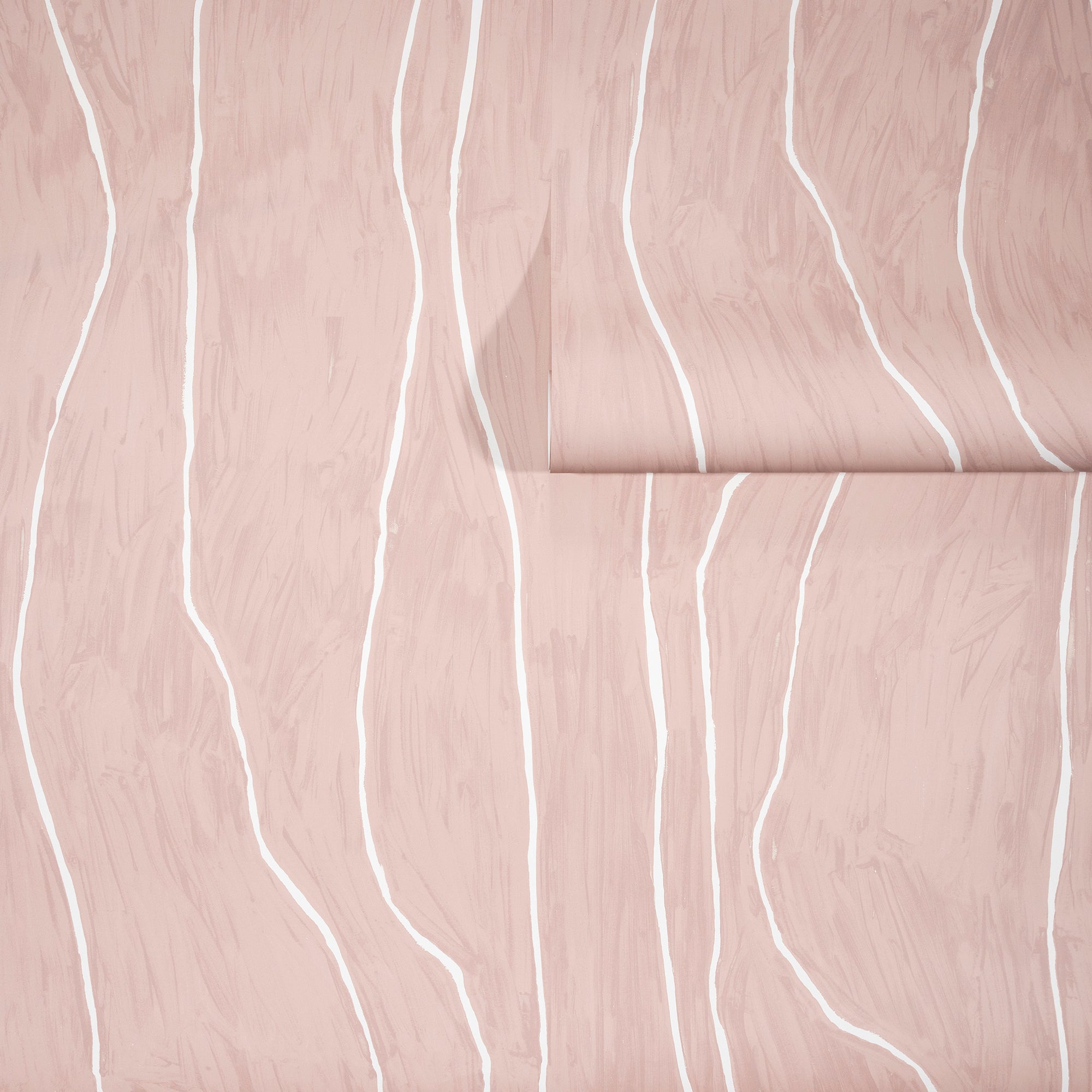 Soft blush-toned wallpaper with flowing white wavy vertical lines, partially unrolled to reveal its organic and elegant pattern.