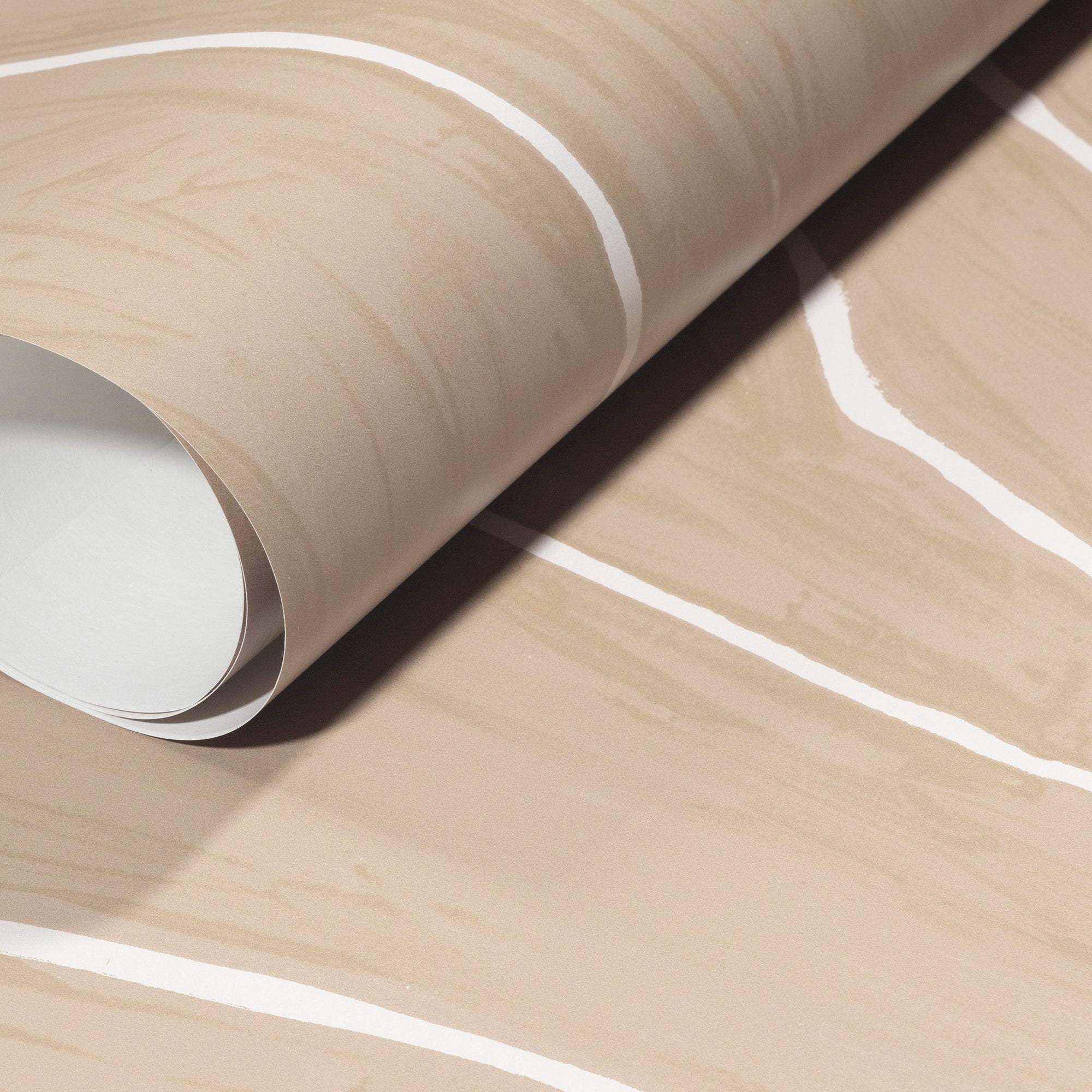 Rolled-up beige wallpaper with organic white wavy stripes, emphasizing its soft texture and timeless design.