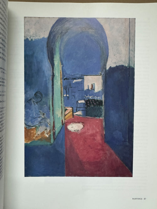  Printed page featuring a painting of a blue interior with an arched doorway opening to a sunlit exterior, a red carpet leading outside, and a seated figure in the shadows, rendered in an impressionistic style.