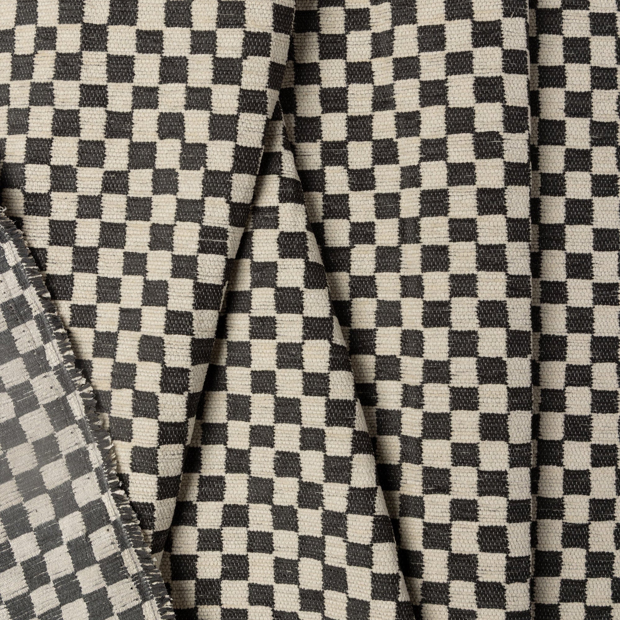 Black and ivory checkerboard jacquard upholstery fabric by the yard, folded showing drape and weight