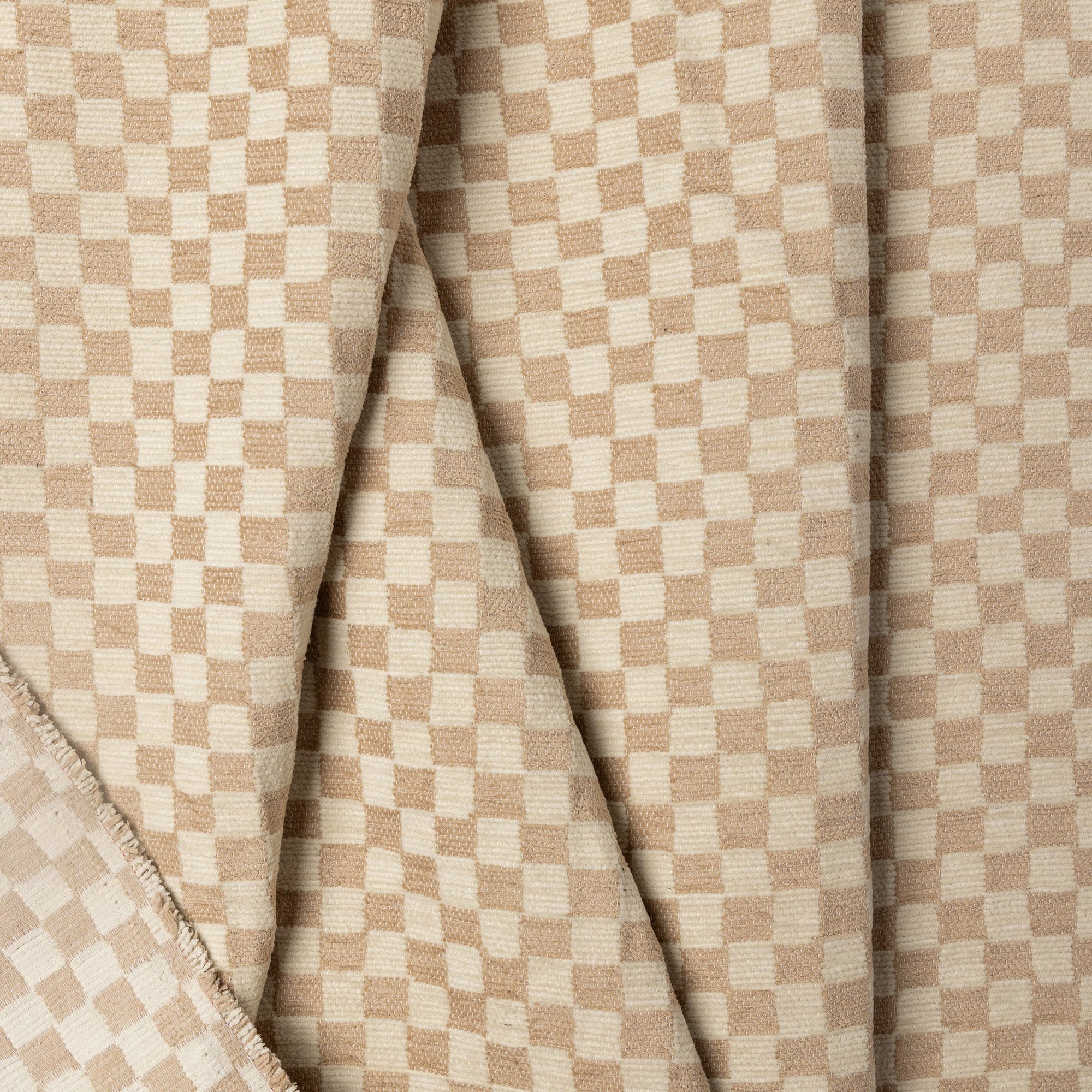 Cream and tan checkerboard jacquard upholstery fabric by the yard, folded showing drape and weight