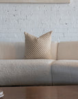 Cream and tan checkerboard throw pillow styled on white boucle sofa