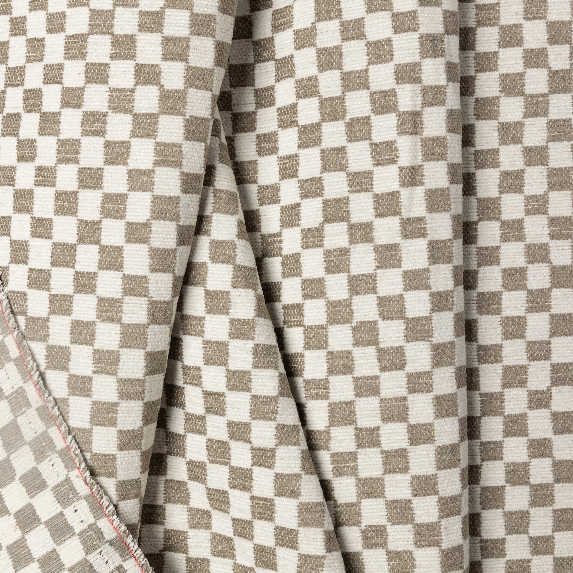 Light gray and cream checkerboard jacquard upholstery fabric by the yard, folded showing drape and weight