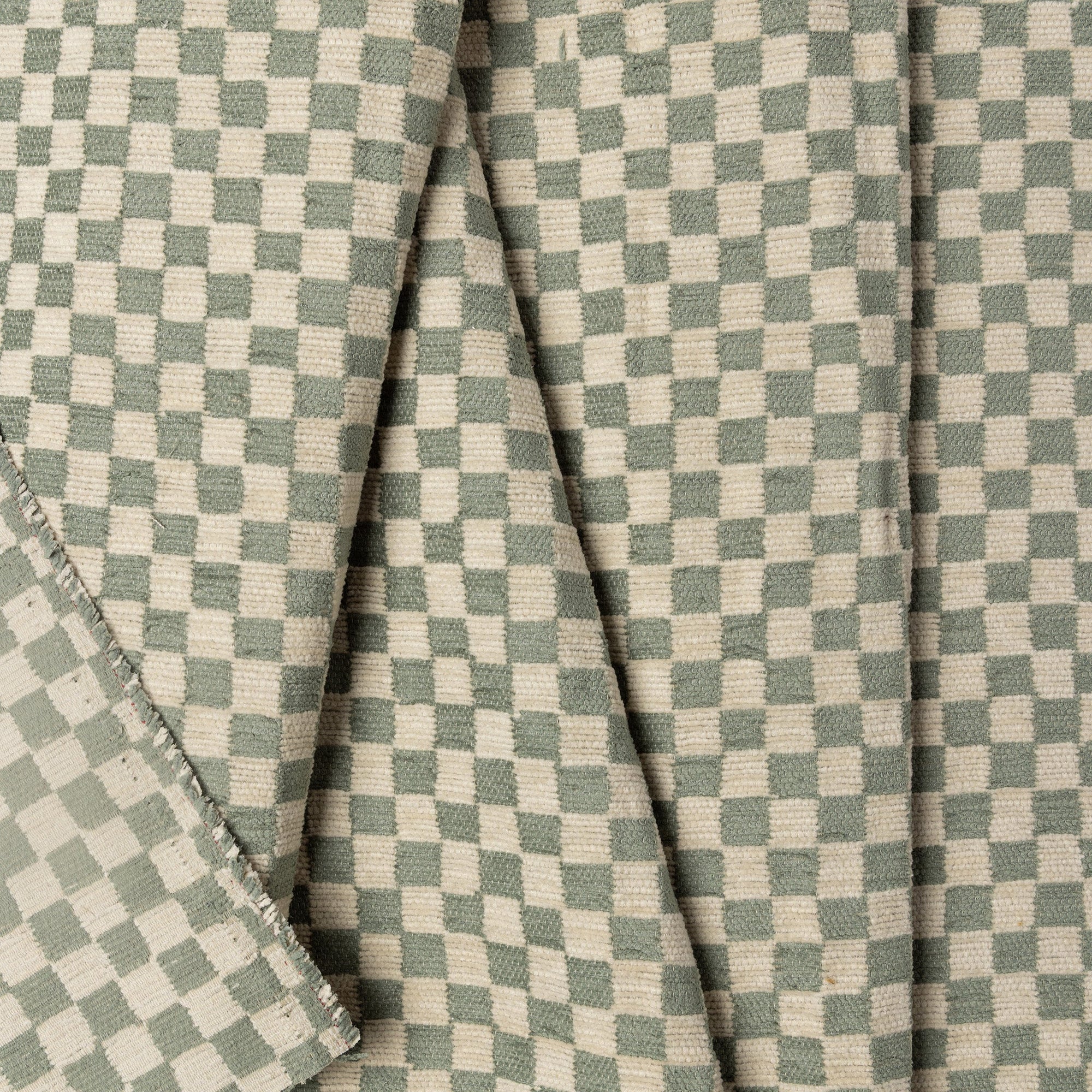 Olive green and cream checkerboard jacquard upholstery fabric by the yard, folded showing drape and weight