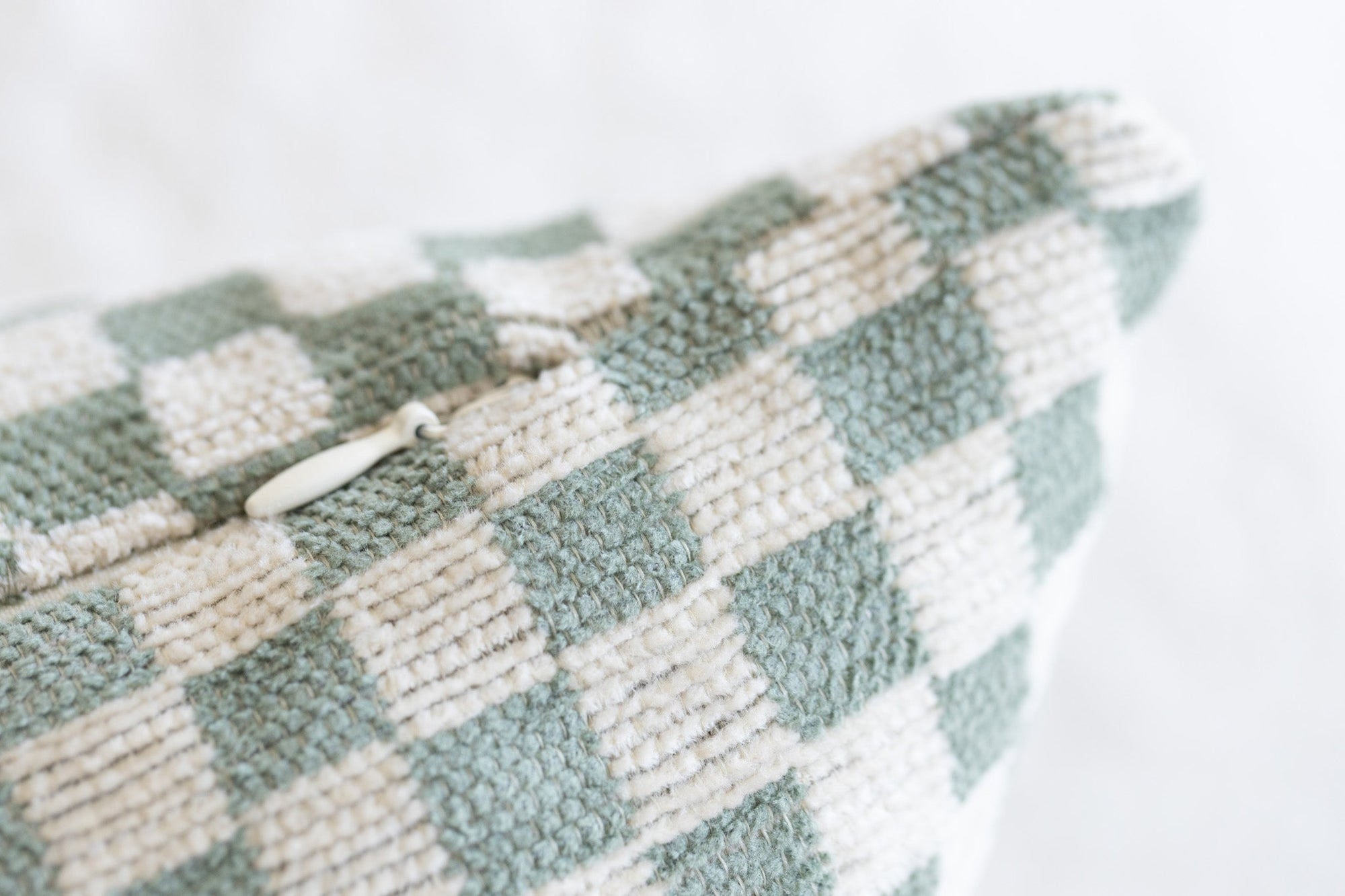 Close-up of woven checkerboard pattern on olive green and cream chenille jacquard throw pillow