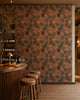 Gray-blue floral on orange wallpaper installed behind a wine bar