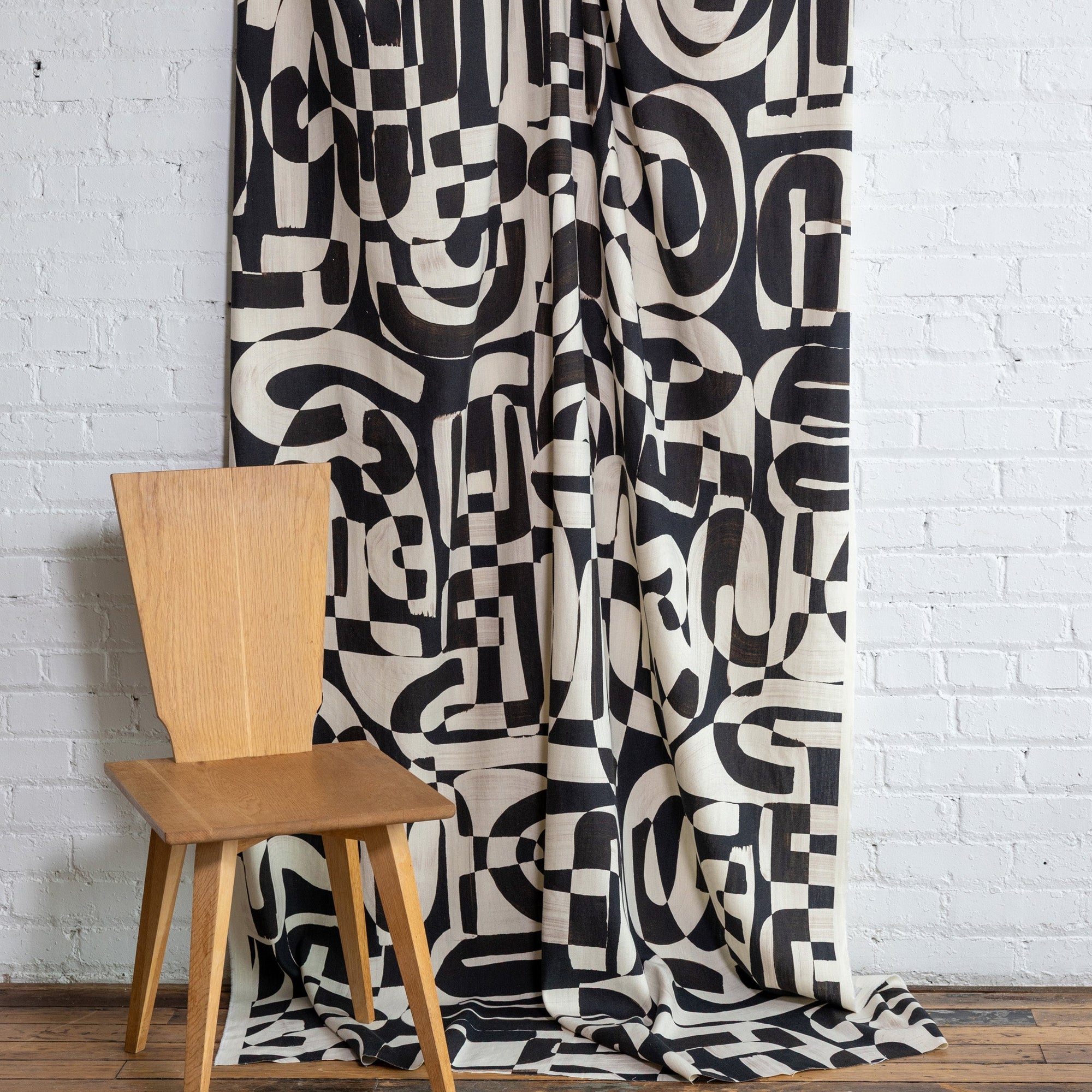 Black and cream abstract printed linen fabric by the yard, draped to show pattern and scale