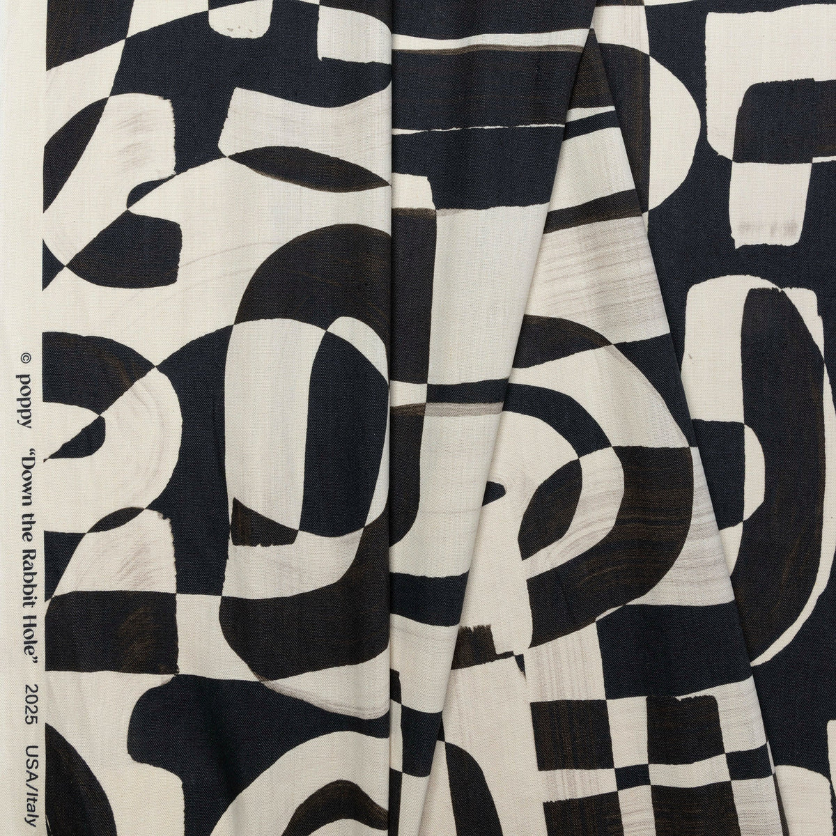 Black and cream abstract printed linen fabric by the yard, folded showing drape and weight