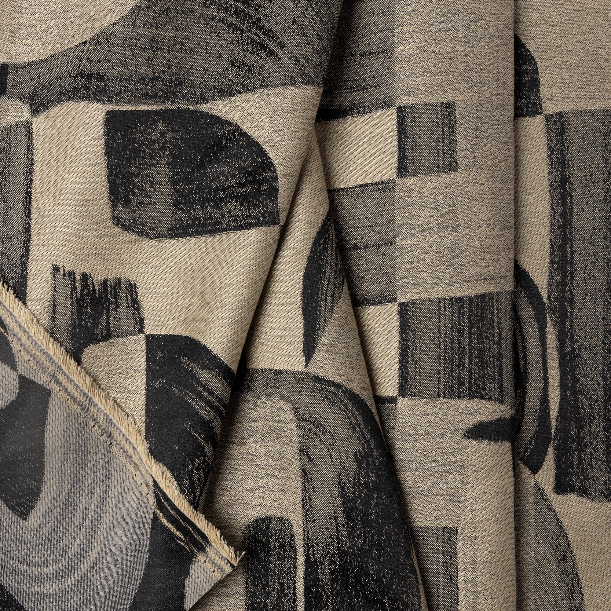 Champagne and black abstract jacquard upholstery fabric by the yard, folded showing drape and weight