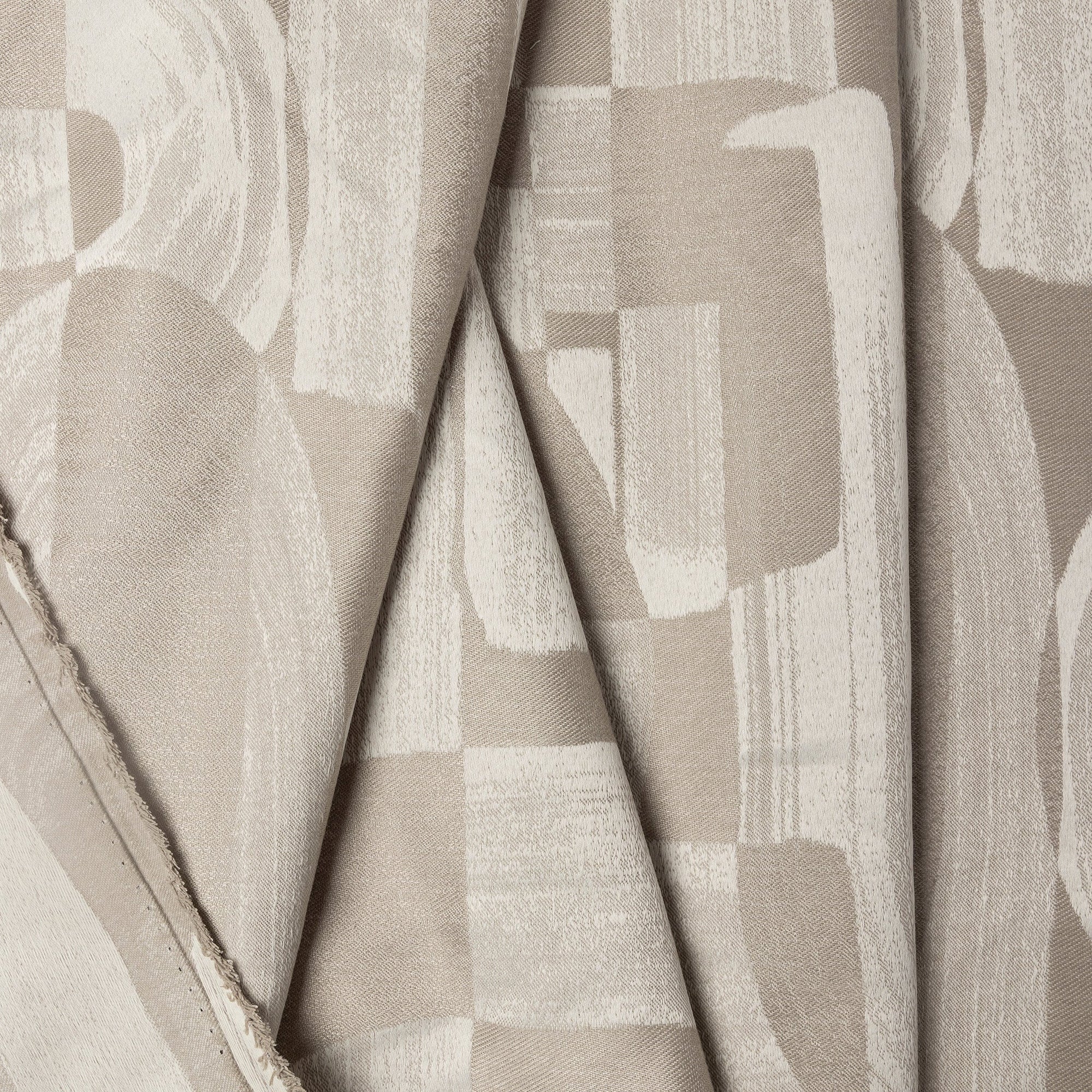 Beige abstract jacquard upholstery fabric by the yard, folded showing drape and weight