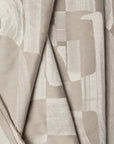 Beige abstract jacquard upholstery fabric by the yard, folded showing drape and weight