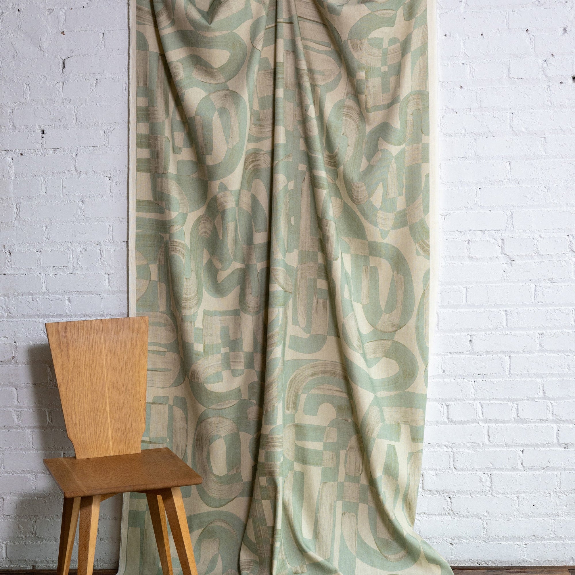 Sage green and cream abstract printed linen fabric by the yard, draped to show pattern and scale