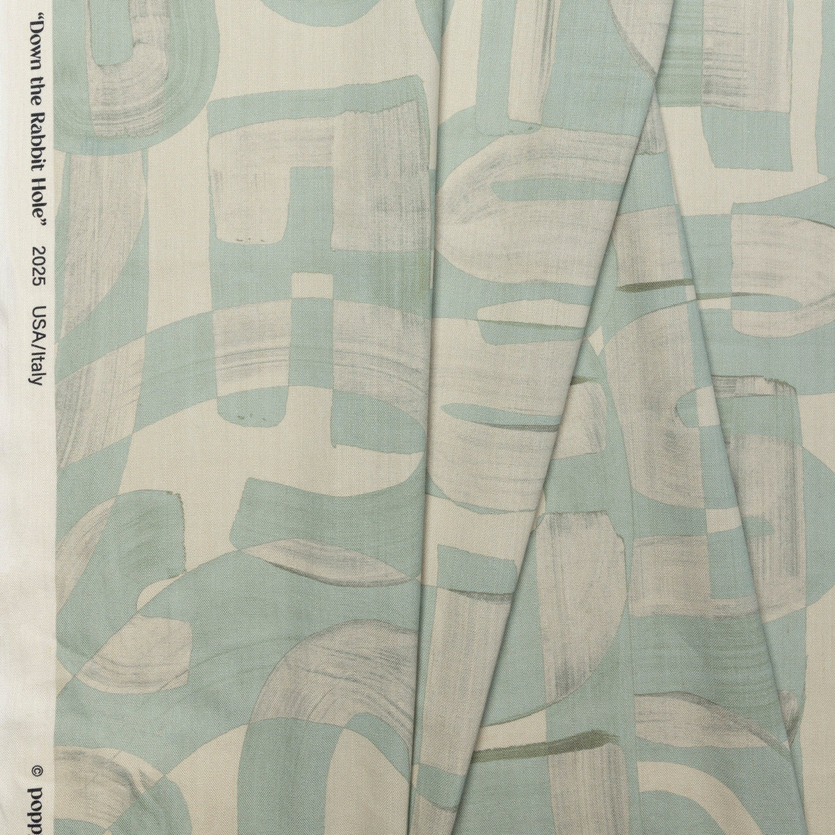 Sage green and cream abstract printed linen fabric by the yard, folded showing drape and weight