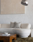 Cream and tan checkerboard pillow styled with cream botanical leaf pillows on white boucle sofa