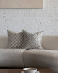 Cream and gray botanical leaf pillow styled with cream checkerboard pillows on white boucle sofa