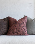 Maroon sunburst pillow with dark brown and silver gray variations on white boucle sofa