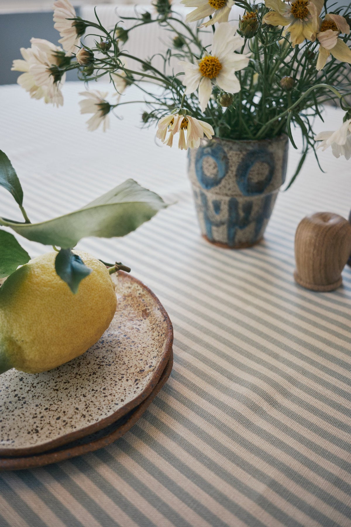 Blue and cream striped linen fabric used as a tablecloth on a nook table set with lemons and ceramics