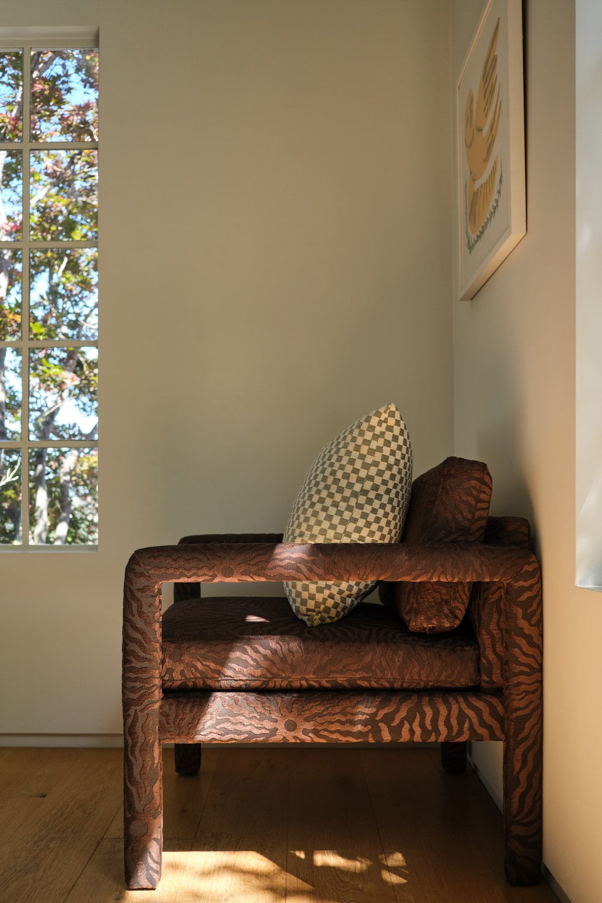 Brown sunburst jacquard fabric upholstered on a chair in a sunlit entry corner