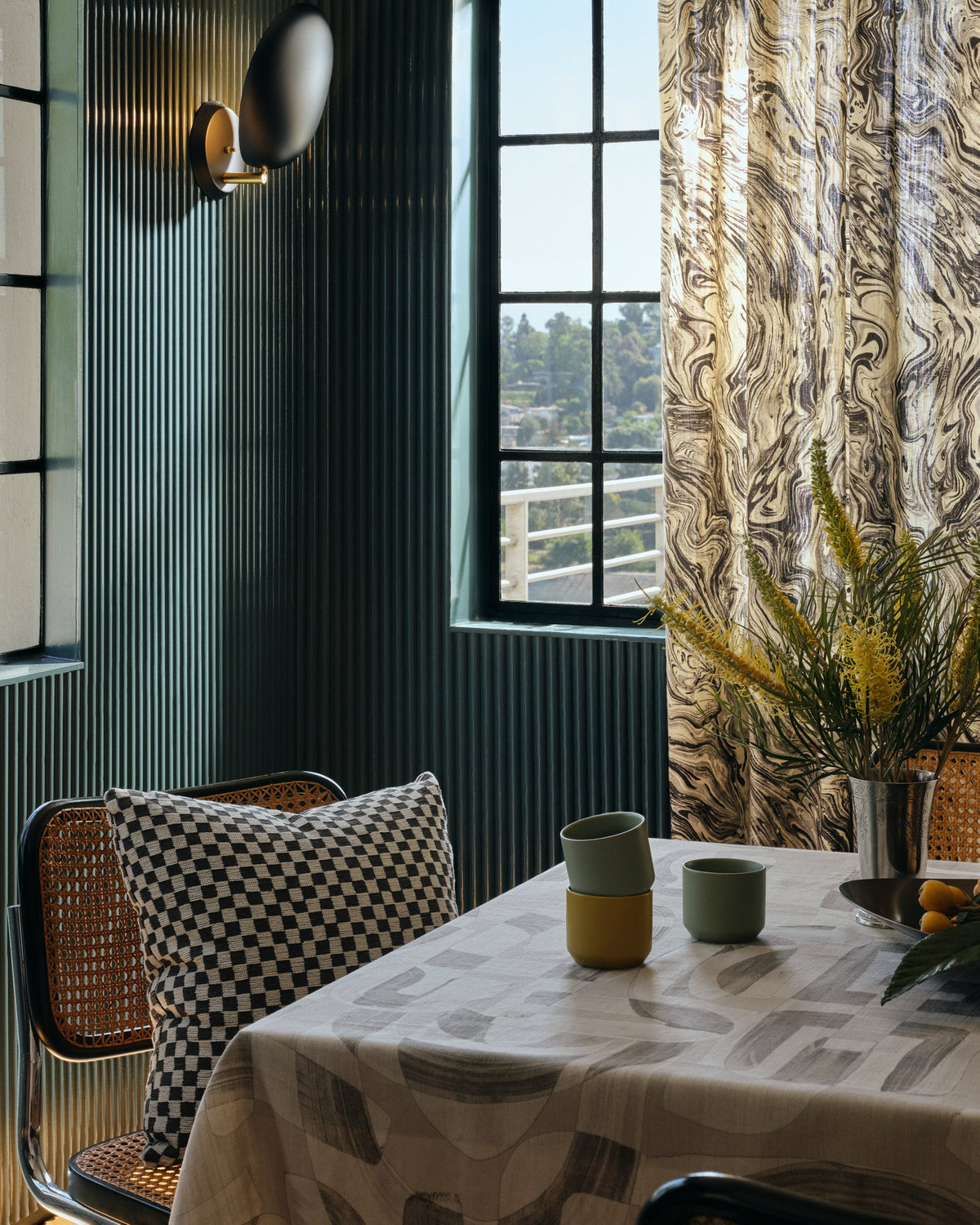 Black and cream checkerboard jacquard fabric made up as a throw pillow in a green panelled dining room