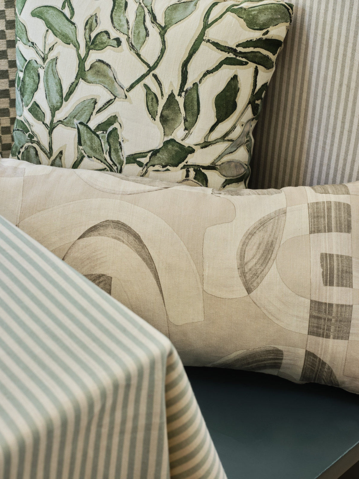 Olive green checkerboard jacquard fabric upholstered on a dining chair layered with pillows in a breakfast nook
