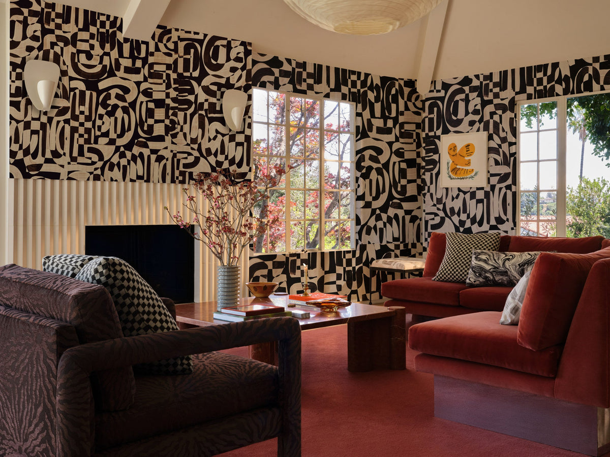 Black and cream checkerboard jacquard fabric made up as a throw pillow across a living room with a velvet sofa