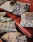 Gray checkerboard jacquard fabric made up as a throw pillow massed with other pillows on a velvet sofa
