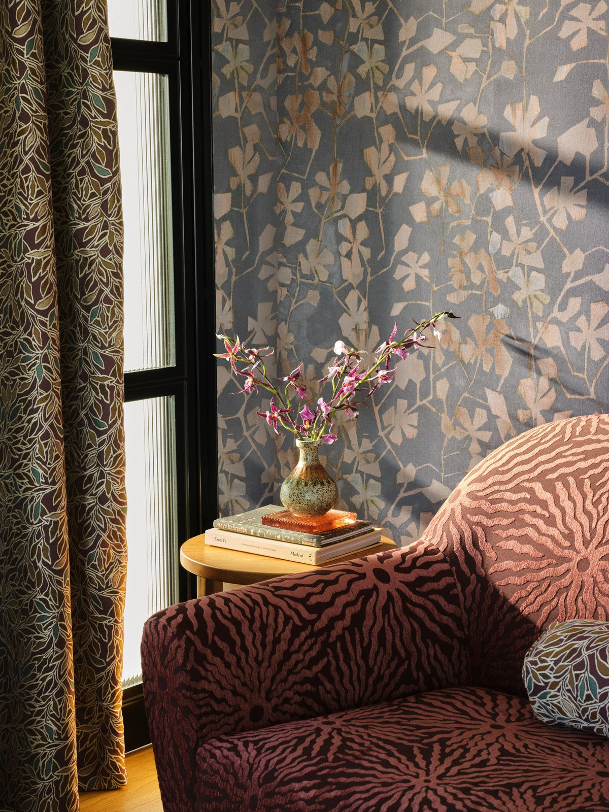 Burgundy sunburst jacquard fabric upholstered on a chair by a window in a sitting room