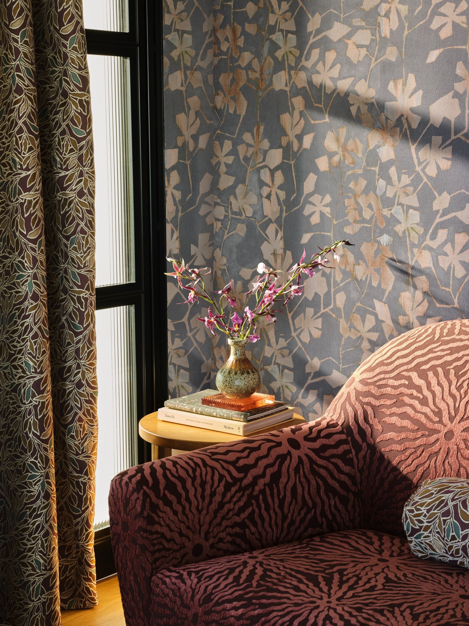 Blue floral cotton wallpaper hung on the wall by a window in a sitting room