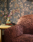 Blue floral commercial wallcovering hung on the wall shown close up on a sofa arm with orchids