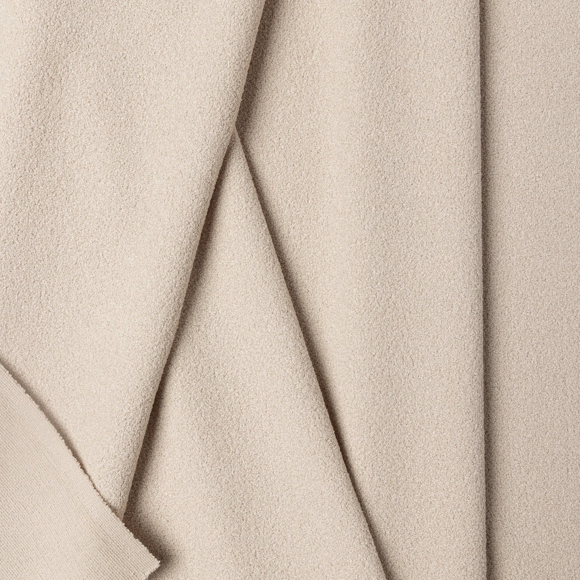 Cream boucle upholstery fabric by the yard, folded showing drape and weight