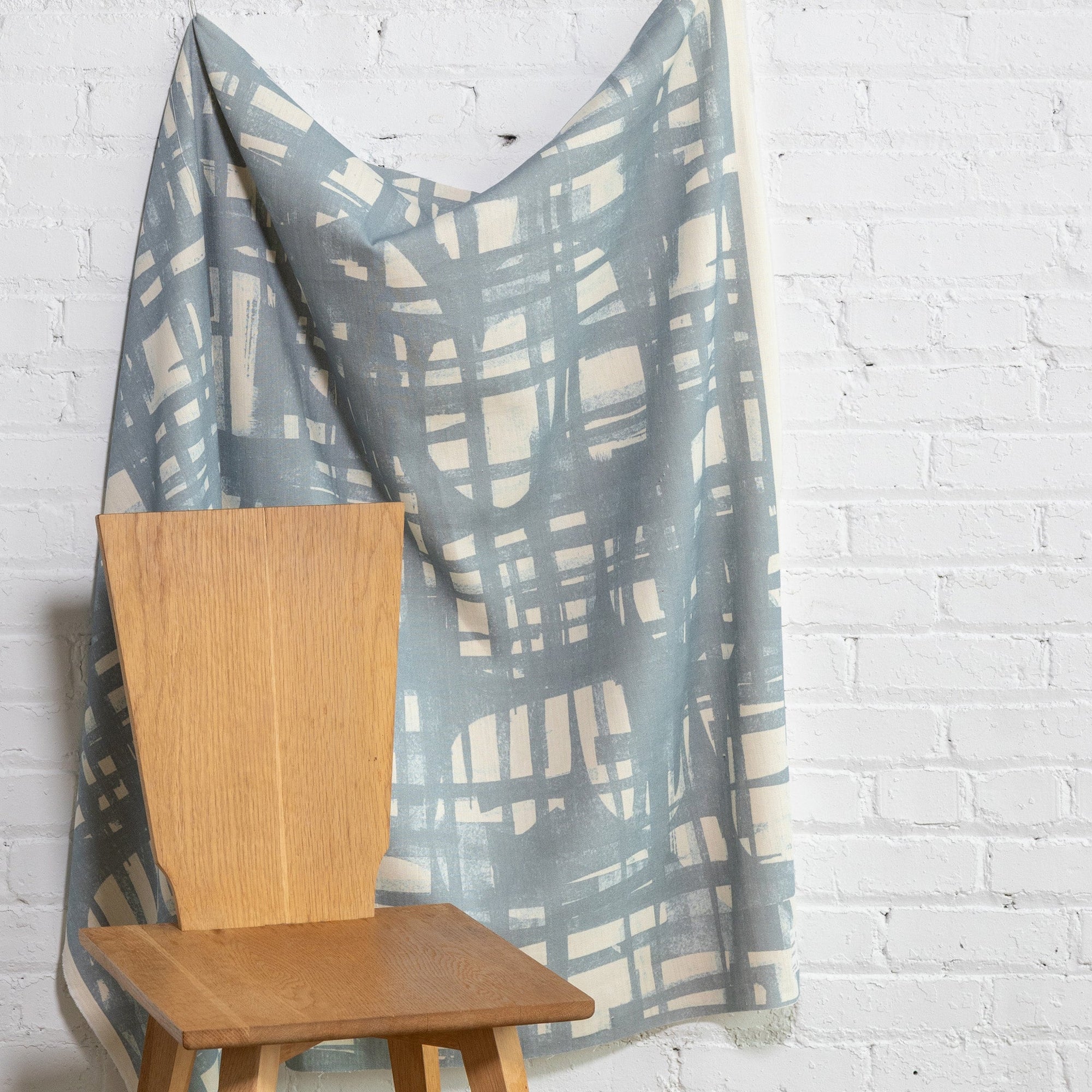 Blue and cream brushstroke crosshatch linen fabric by the yard, draped to show pattern and scale