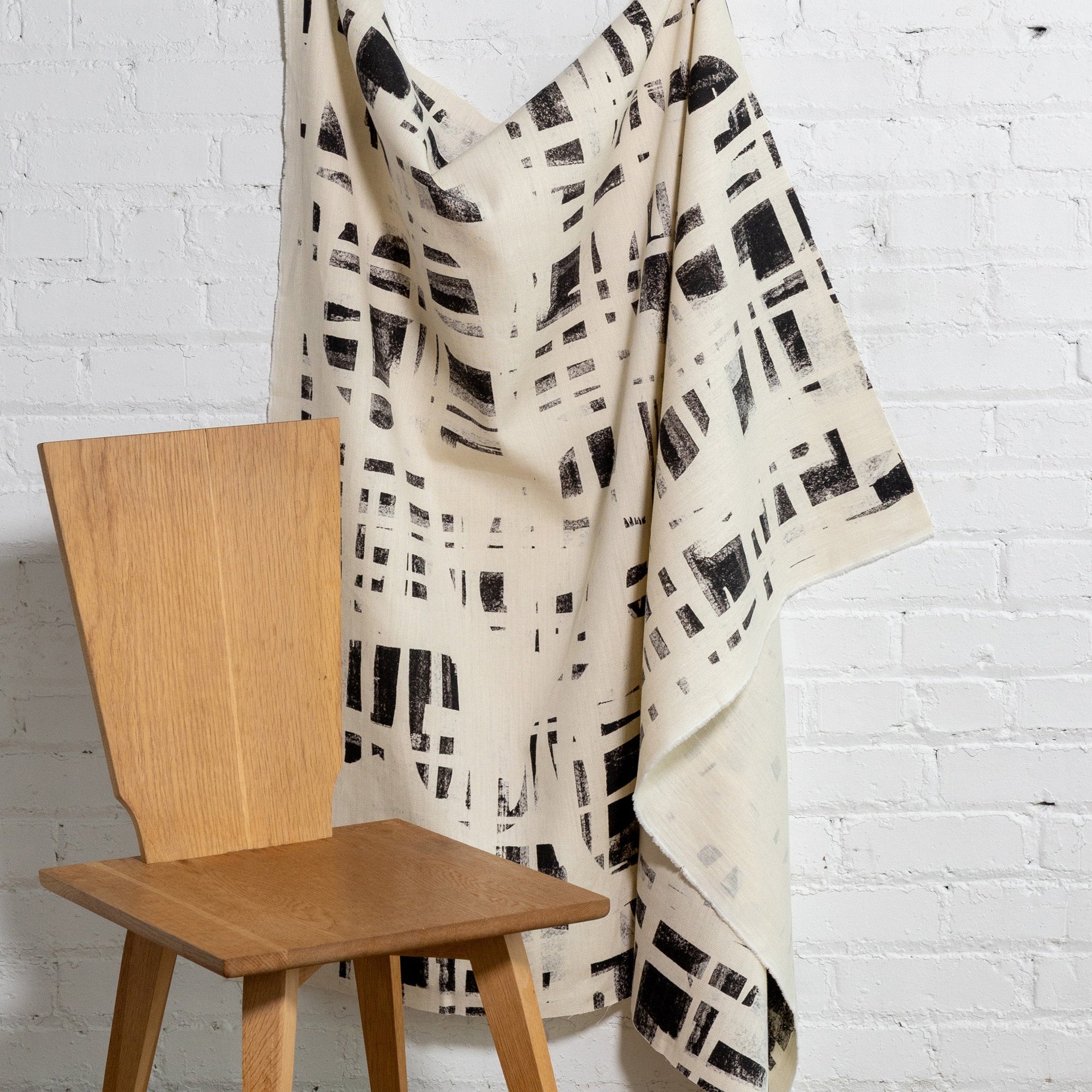 Cream and black brushstroke crosshatch linen fabric by the yard, draped to show pattern and scale