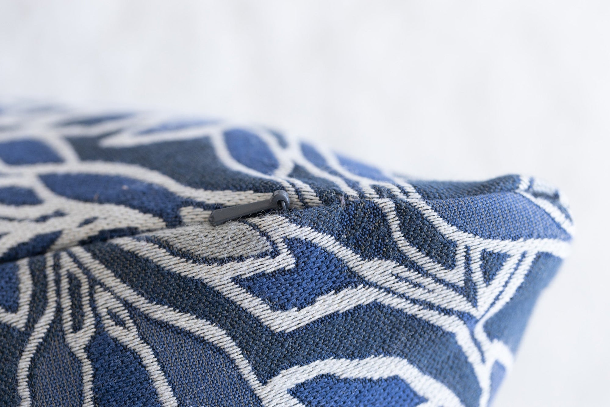 Close-up of woven botanical leaf pattern on blue and cream jacquard throw pillow