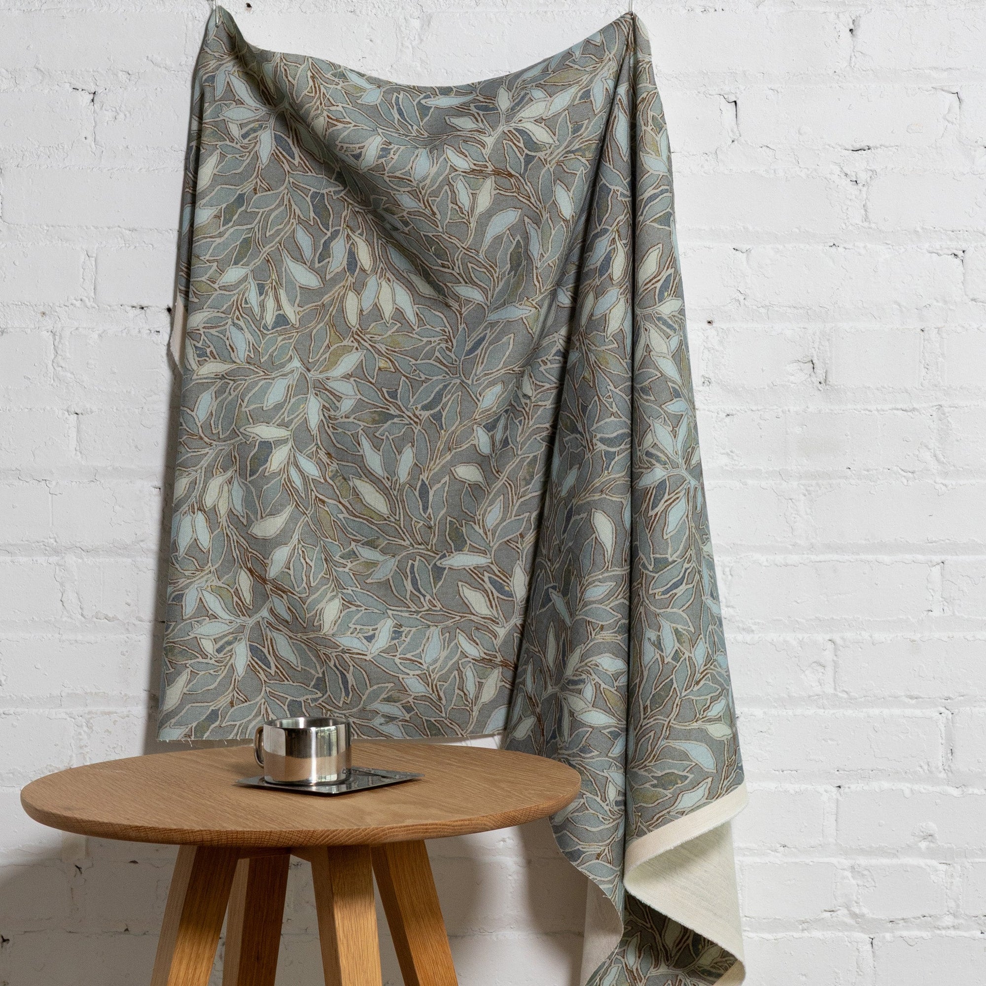 Blue botanical leaf printed linen fabric by the yard, draped to show pattern and scale