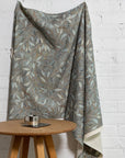 Blue botanical leaf printed linen fabric by the yard, draped to show pattern and scale