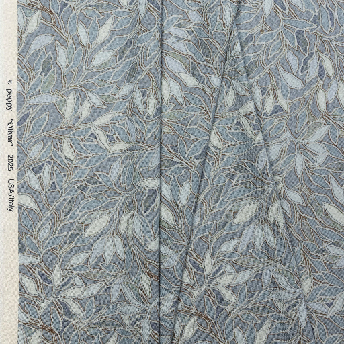 Blue botanical leaf printed linen fabric by the yard, folded showing drape and weight