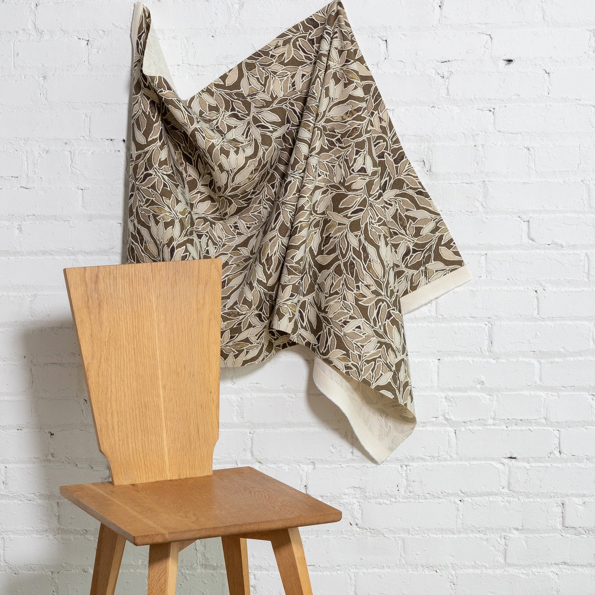 Brown botanical leaf printed linen fabric by the yard, draped to show pattern and scale