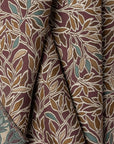 Deep maroon with teal botanical leaf jacquard upholstery fabric by the yard, folded showing drape and weight