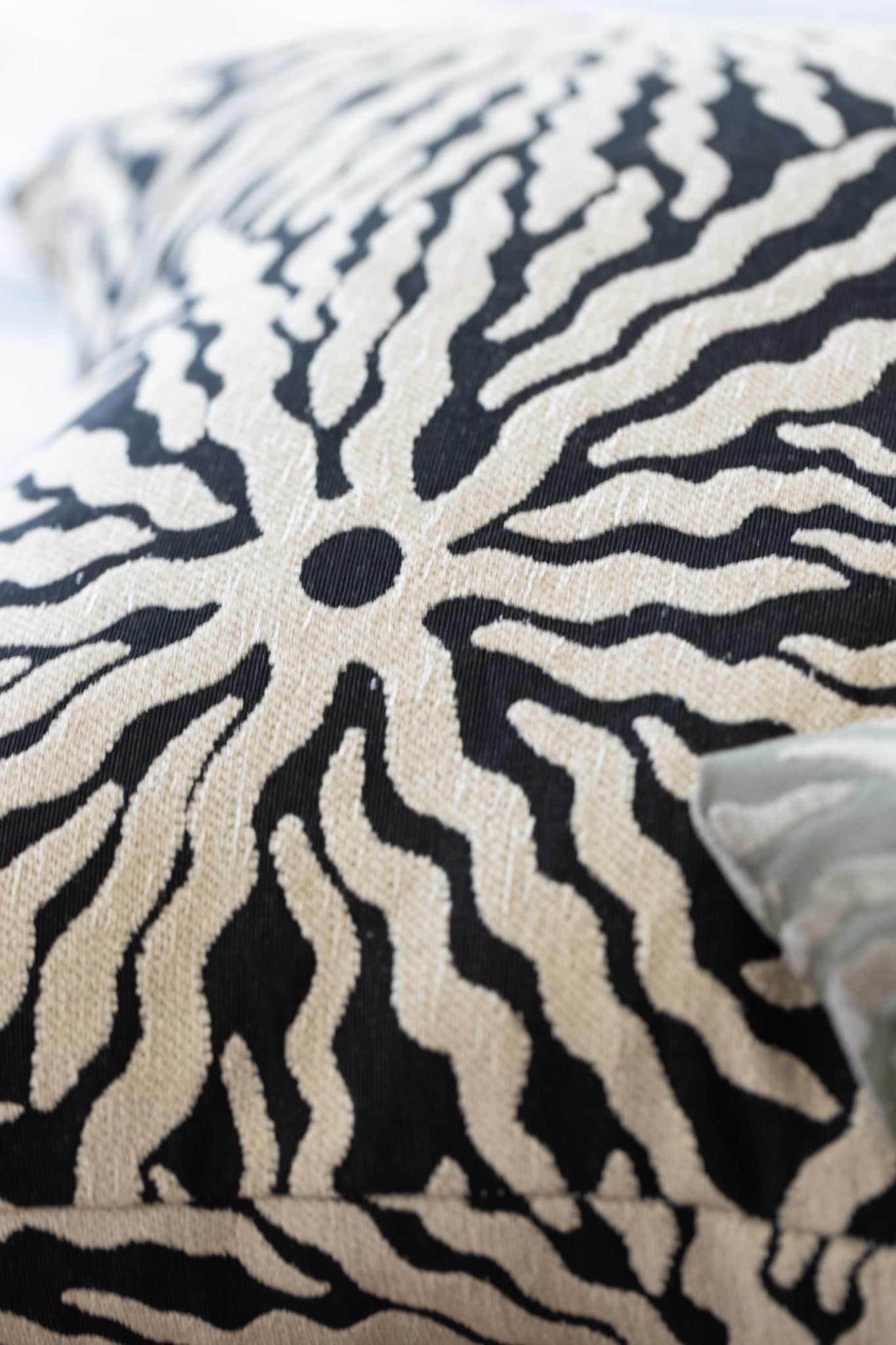 Close-up of woven sunburst pattern on black and ivory jacquard throw pillow