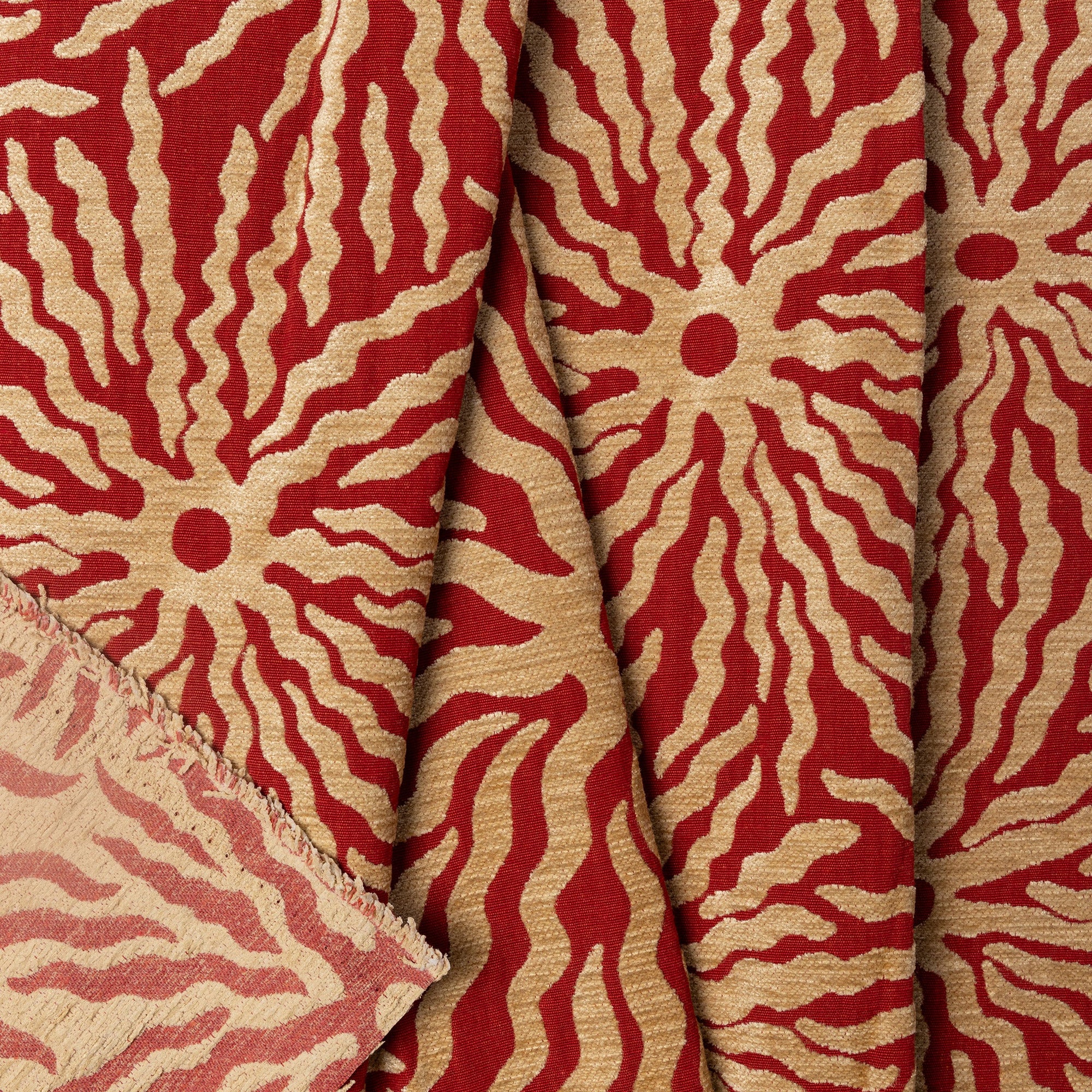 Red and gold sunburst jacquard upholstery fabric by the yard, folded showing drape and weight