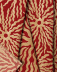Red and gold sunburst jacquard upholstery fabric by the yard, folded showing drape and weight
