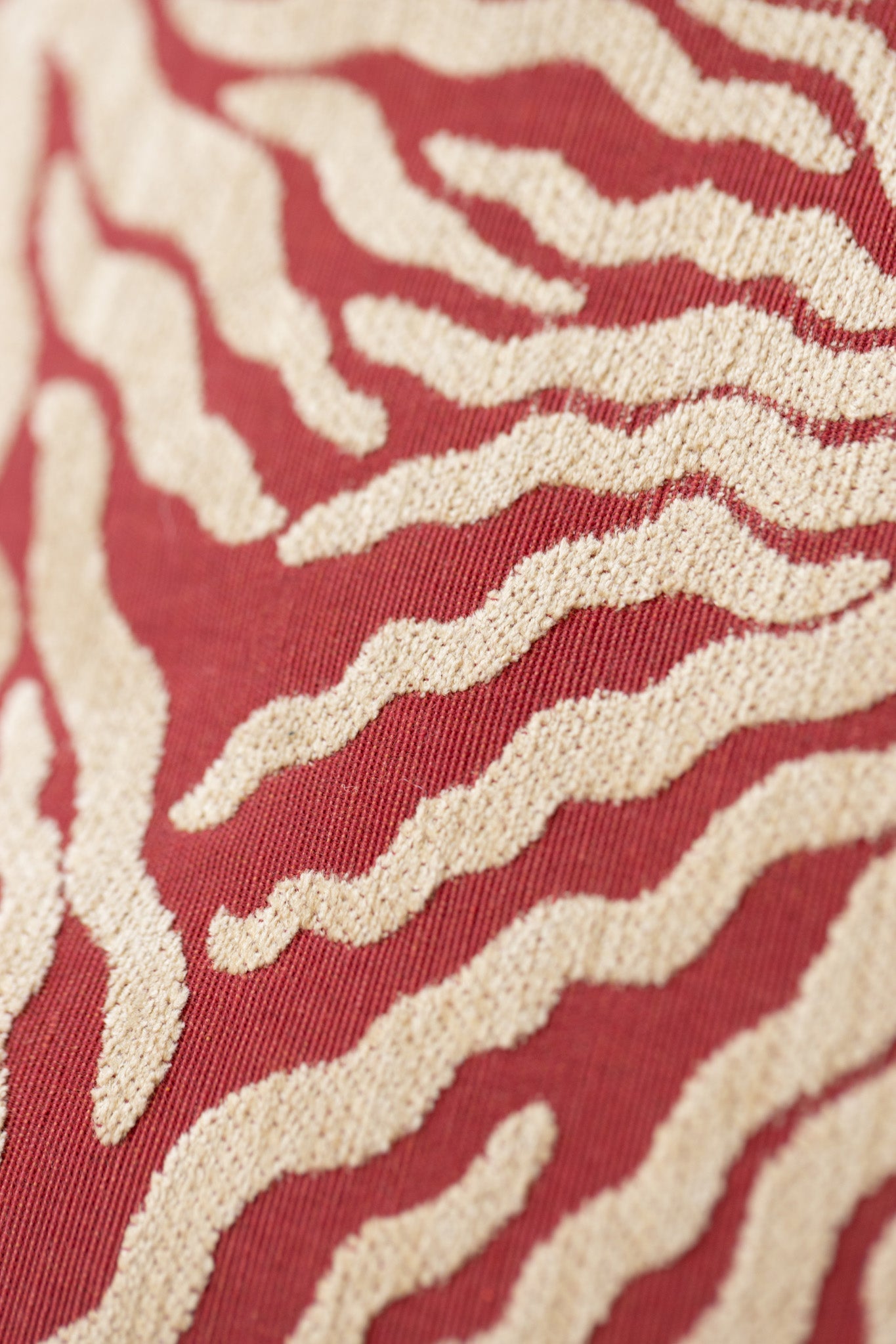 Close-up of woven sunburst pattern on red and cream jacquard throw pillow