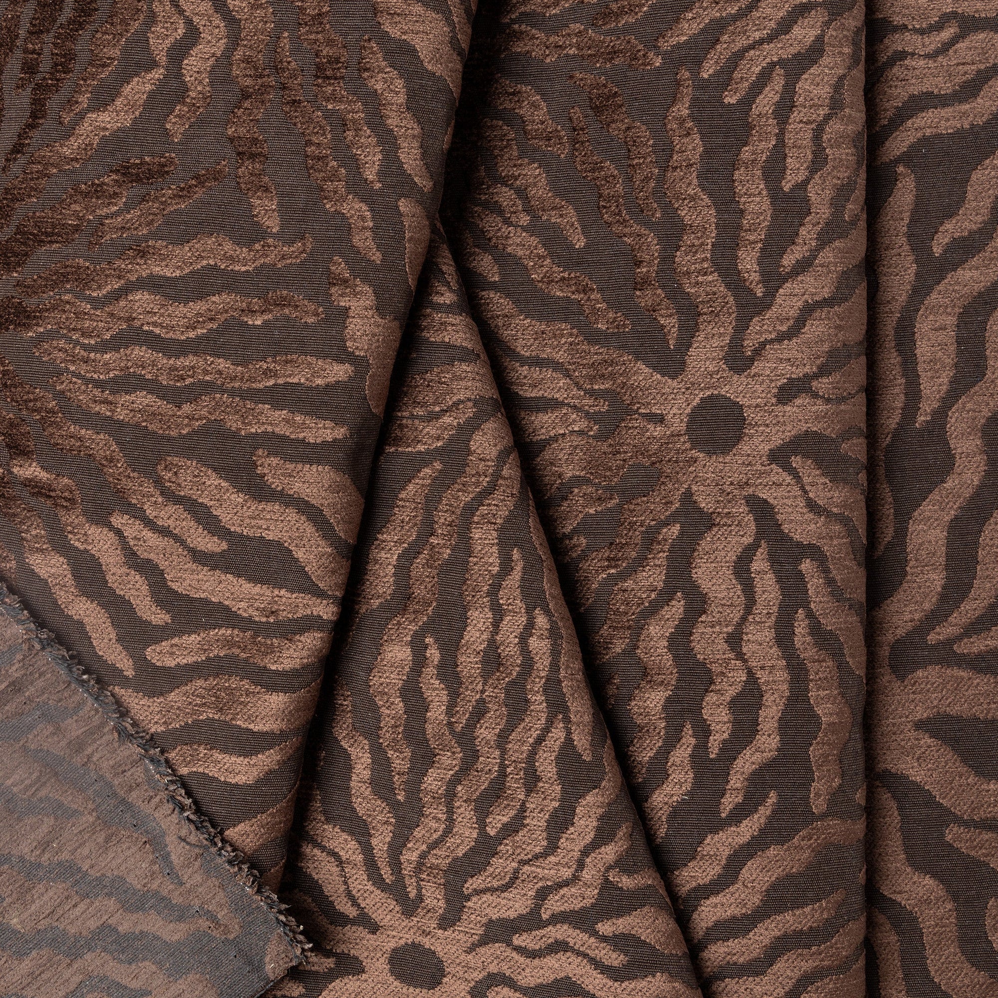 Dark brown sunburst jacquard upholstery fabric by the yard, folded showing drape and weight