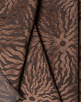 Dark brown sunburst jacquard upholstery fabric by the yard, folded showing drape and weight