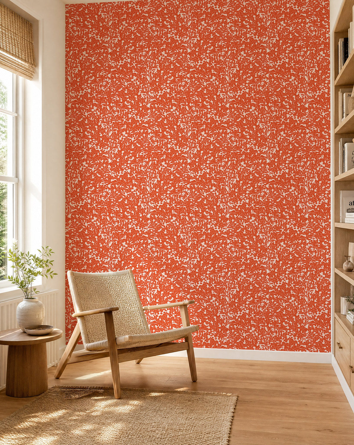 Orange-red and white abstract squiggle wallpaper installed in a sunlit reading nook