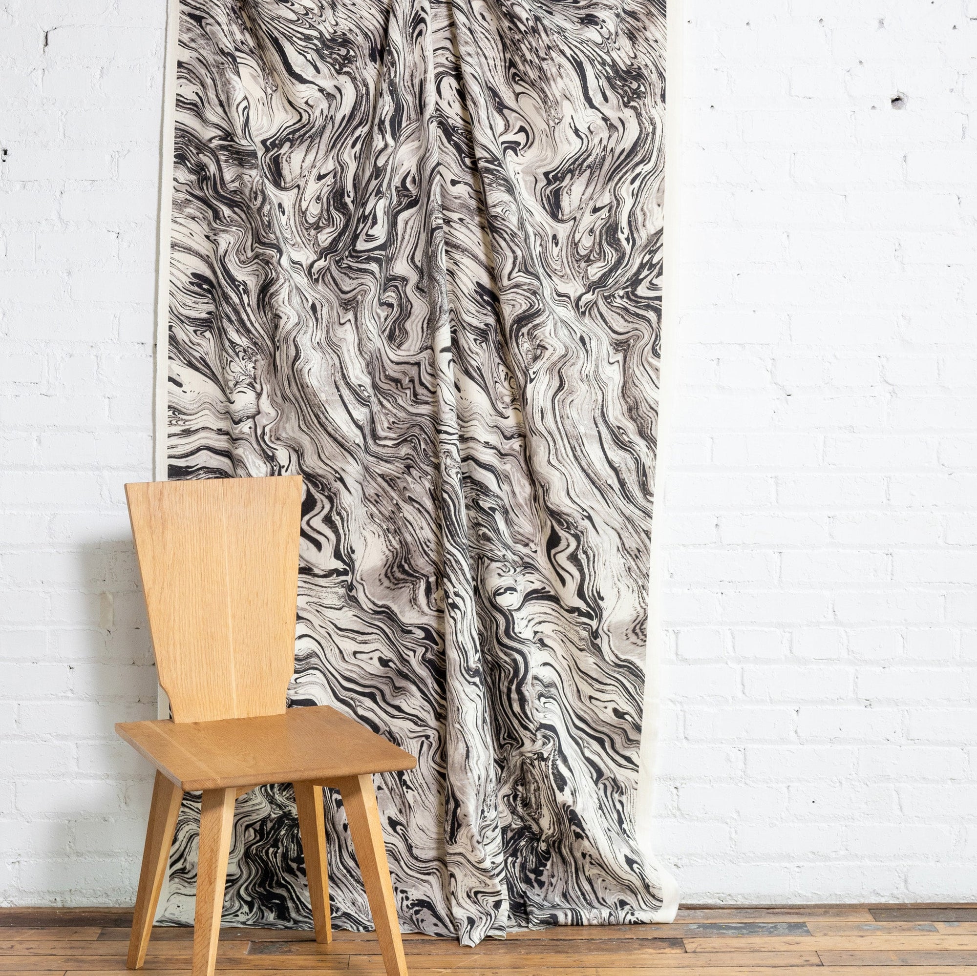 Black and cream marbled abstract linen fabric by the yard, draped to show pattern and scale
