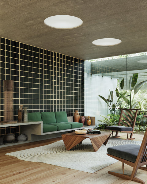 Contemporary living space featuring black and tan grid-patterned wallpaper, a floating concrete sofa with green cushions, wooden accent chairs, and large windows overlooking lush greenery, creating a serene and modern Japandi atmosphere.